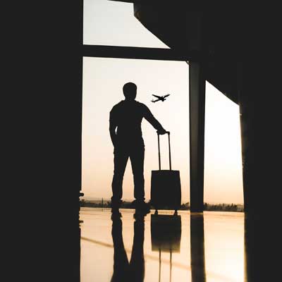 Man at the airport looking out the window at sunset